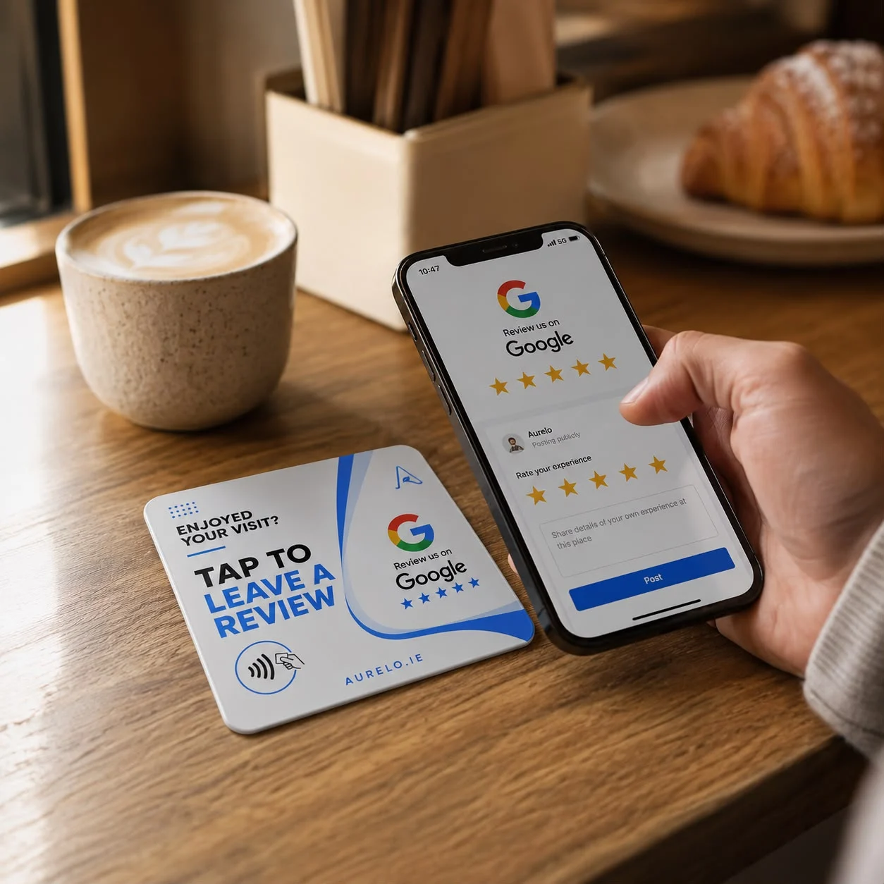 An aurelo review card on a café table beside a coffee, with a customer's phone open on the Google review screen.